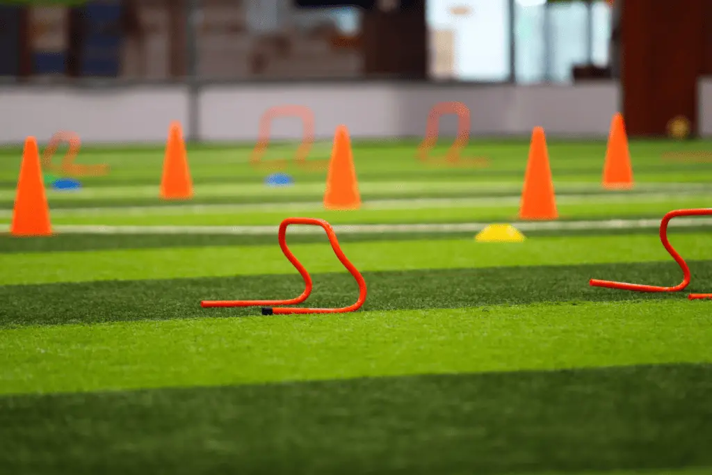 A set of agility hurdles and cones laid out on a soccer field during physical training.