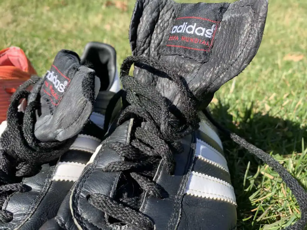 A picture of black and white leather Adidas soccer cleats.