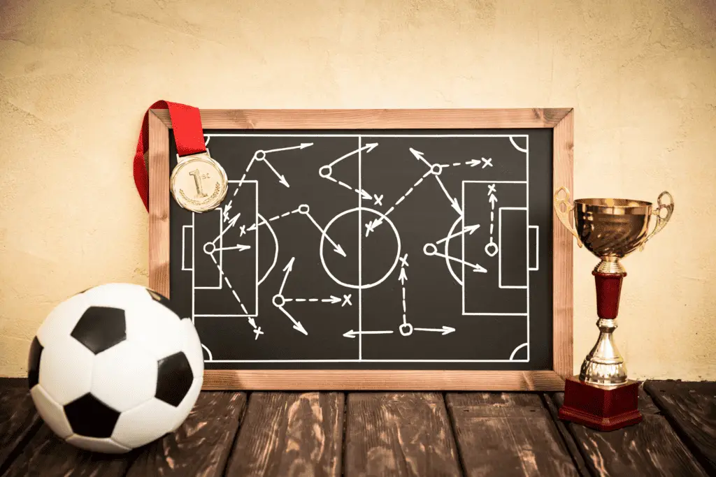 A picture with a soccer ball, trophy, 1st place medal, and a chalkboard displaying soccer strategy.