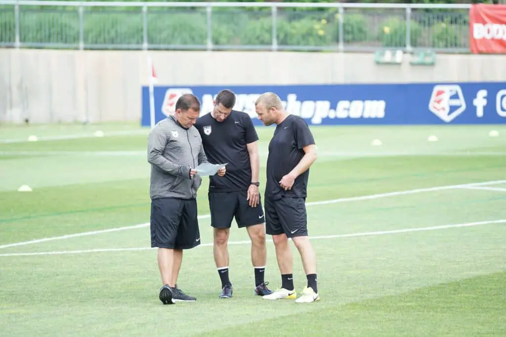 Three coaches discussing soccer tactics.