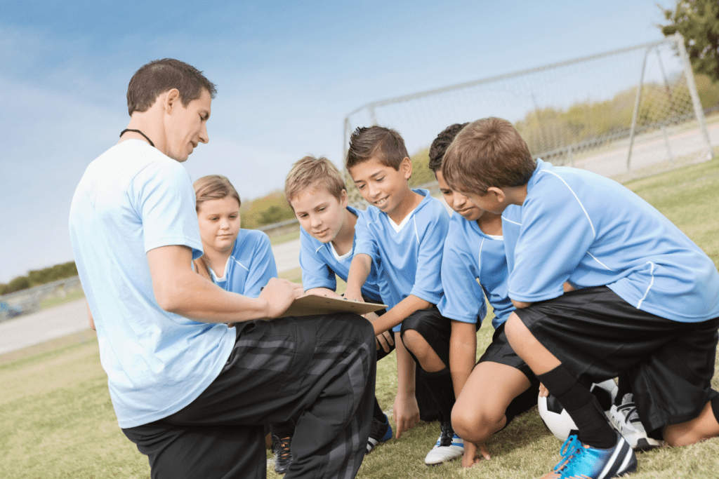 A group of young soccer players gathered around their coach during tactical training