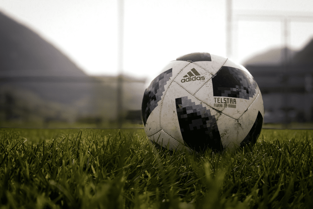 A black and white Adidas soccer on a grass field.